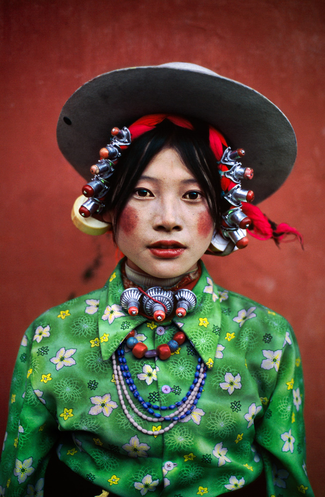 Tibet, 1999, Tibet-10002. A colorful village girl participates in a rural horse festival in Eastern Tibet. MAX PRINT SIZE: 40X60 Woman at horse festival, Tagong, Tibet, 1999 -Untold (pg. 200) "Woman at horse festival, Tagong" - The Path to Buddha, a Tibetan Pilgrimage" (pg. 131) McCurry pictured this woman at the famous Tagong horse festival. It is a vivid image. The emerald green shirt, adorned with delicate white flowers, contrasts sharply with the rich blues and reds of the necklaces and rouge applied to the woman's cheeks and lips. All set against a blood red backdrop, it makes for an intoxicating picture. Phaidon, Looking East, The Path to Buddha, Iconic Images, final book_iconic, iconic photographs Magnum Photos, NYC31808, MCS1999007K001 Each portrait speaks a thousand words about its subject and their world. The intricately carved beads of a festival-goer in Kham, Tibet, unwittingly demonstrate as skill in handicraft that has been almost entirely lost in the West. The striking robes and ceremonial clothing of monks and worshippers at temple are vividly colored by the very same natural dyes and spices that first lured Western traders to Asia. McCurry, Steve. (2006). Looking East. New York: Phaidon Press Inc., 61 IG: I photographed this young woman at horse festival in Tagong, Tibet. Tibetan people have a great sense of style, an innate fashion sense. They come out of the mountains wearing amazing hats, make-up, and jewelry. Young Woman at a Horse Festival, Tagong, Tibet, 1999 (Looking East, 62) The Path to Buddha_Book Looking East_Book Iconic_Book PORTRAITS_book Untold_book final print_MACRO final print_Milan final print_Sao Paulo final print_Birmingham final print_HERMITAGE final print_Zurich final print_Ankara PORTRAITS_APP Stern_Portfolio Fine Art Print retouched_Sonny Fabbri 7/2015