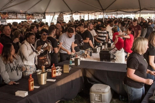 A crowd shot of event-goers under a tented area to taste wings at Wing Fest 2018