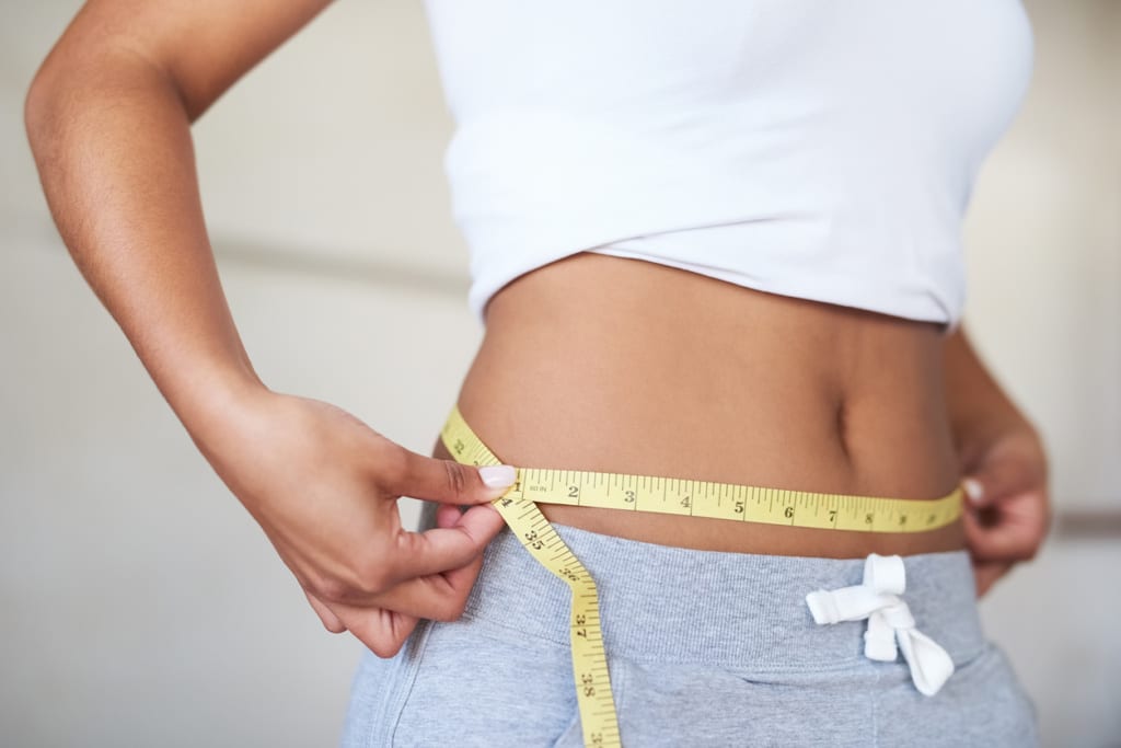 Cropped shot of a young woman measuring her waist in the bathroom for weight loss.